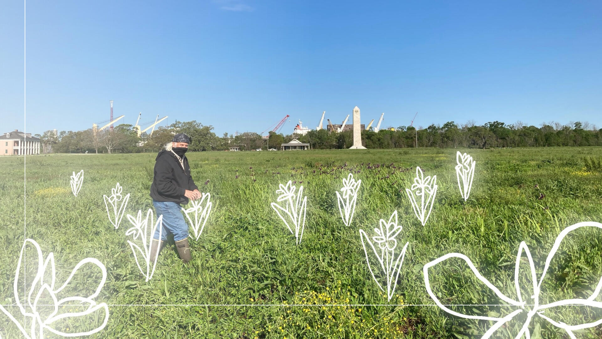 A man wearing a neck gaiter and tall rubber boots walks through a tall green field of grass. Several large cranes are visible in the far distance against a blue sky. Hand drawn neon flowers surround him.